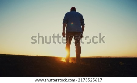 agriculture. a male farmer in rubber boots walks on a plowed agricultural floor. farm worker walking home after harvest at the end of the working day legs in rubber boots agriculture sun Royalty-Free Stock Photo #2173525617