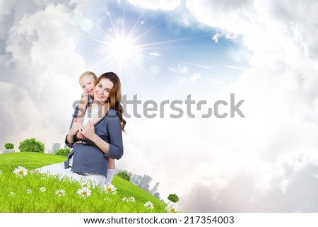 Happy mother with daughter sitting on green grass