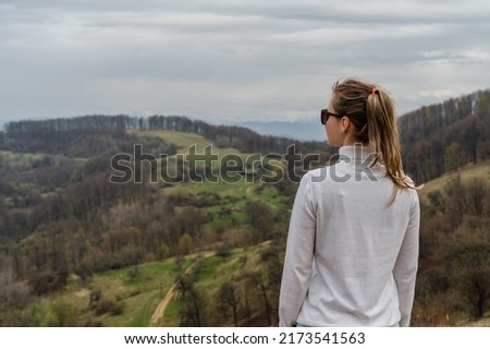 Beautiful mountains and standing young woman on top hills. Landscape with mountain peak, forest. Travel concept