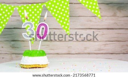 Beautiful festive background with the number 30 with a cake and lit candles, space saving for any holiday. Garland with birthday decorations for a postcard.Decorations are multi-colored festive.