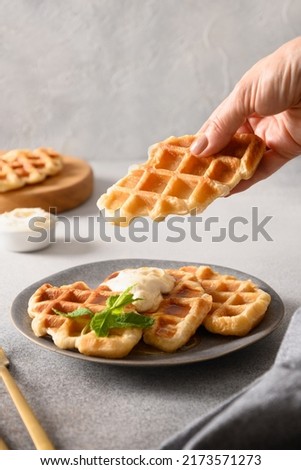 Woman take croffles, delicious breakfast. Croissant as waffle. Korean street food. Vertical format. Close up. Royalty-Free Stock Photo #2173571273