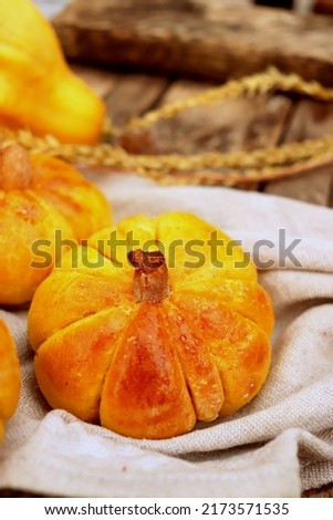 delicious sweet buns in the shape of a pumpkin baked close-up on a wooden surface, pumpkin pastries
