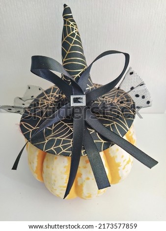 Natural ripe pumpkin decorated with an elegant witch's hat with a bow and veil. Halloween house decoration concept