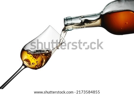 Digestive tulip of premium alcohol. The drink is poured from a bottle into a glass. Isolated on a white background. Royalty-Free Stock Photo #2173584855