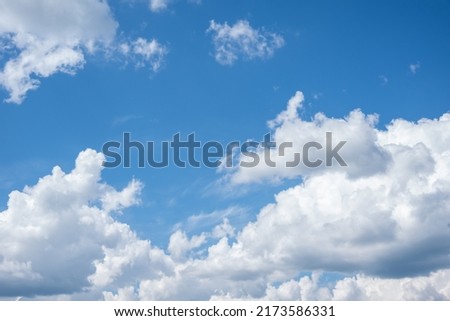Blue sky background with white fluffy cumulus clouds. Panorama of white fluffy clouds in the blue sky. Beautiful vast blue sky with amazing scattered cumulus clouds. Royalty-Free Stock Photo #2173586331