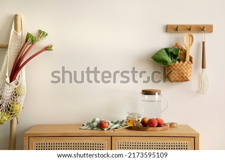 Interior design of kitchen space with copy space, rattan commode,  ladder, rhubarb, vegetables, food and kitchen accessories in modern home decor.  Template. 