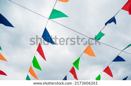 Small, multicolored flags on a blue sky background. Colorful background. Carnival festival, decoration of a park or a street festival.