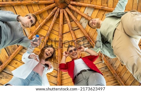 Fun with friends. Low angle view of four cheerful young people looking at camera while standing