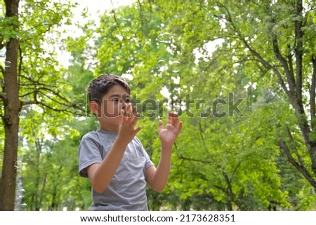 Child catches soap bubbles in the park in summer
