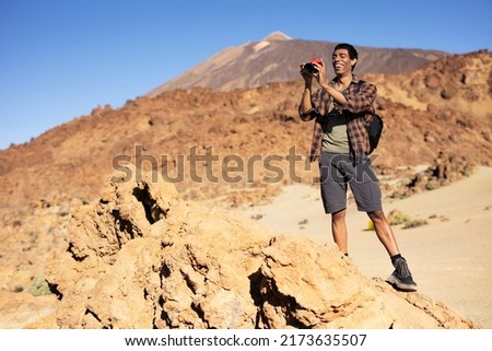 Young man taking pictures on a road trip. Man making memories on the mountain.	