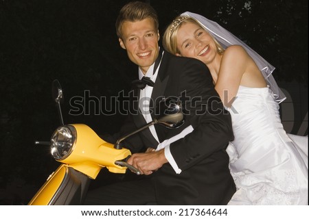 Portrait of a newlywed couple on a motor scooter and smiling