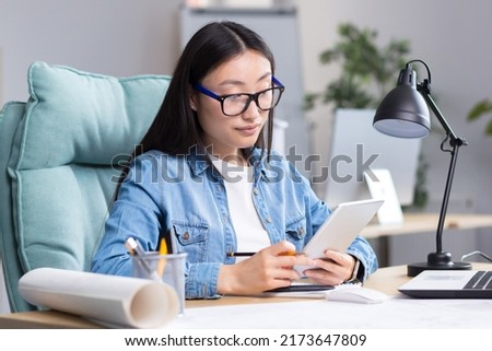 Young Asian woman designer working in office using tablet, working on drawing project.
