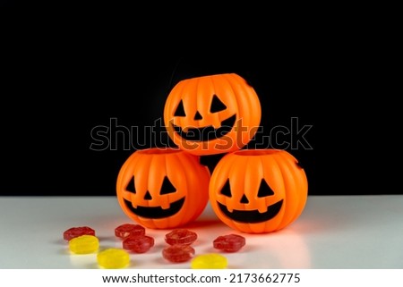 Three halloween pumpkins with colorful candies on black background