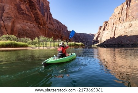 Adventurous Woman on a Kayak paddling in Colorado River. Glen Canyon, Arizona, United States of America. American Mountain Nature Landscape Background. Adventure Travel Royalty-Free Stock Photo #2173665061