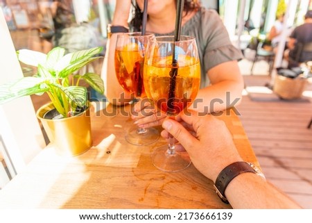 Two cocktail glasses in the middle age man and woman hands in a outdoors cafe.Summer vacation concept.Closeup.