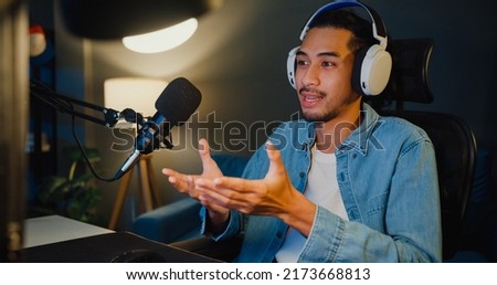Happy asia guy blogger music influencer record a podcast on computer with headphones and microphone talk with audience in living room home studio at night. Stay at house, Content creator concept. Royalty-Free Stock Photo #2173668813