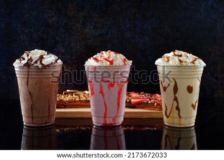 Malted milkshakes of different flavors and crepes on a dark background. Royalty-Free Stock Photo #2173672033
