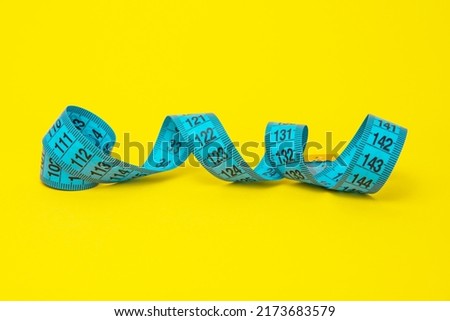 Blue tape measure diet concept on yellow background with copyspace