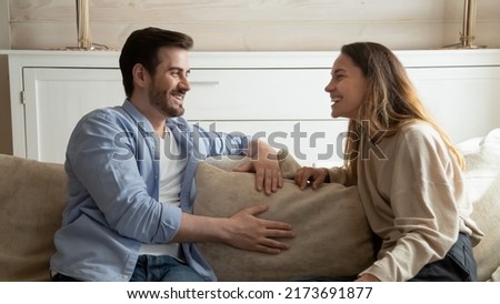 Resting at home together. Pleasant young millennial family couple, brother and sister, diverse friends sitting on cozy sofa at living room relaxing together talking joking having cheerful conversation Royalty-Free Stock Photo #2173691877