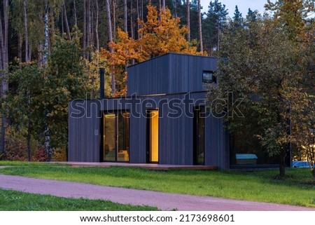 Modular apartment of frame type , sheathed in wood against the background of an autumn forest . Mobile eco-friendly space for living and tourism . Royalty-Free Stock Photo #2173698601