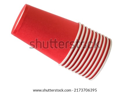 Stack of disposable cups is on a white background. It's an isolated view of pink paper glass. It's a stack of red glasses.
