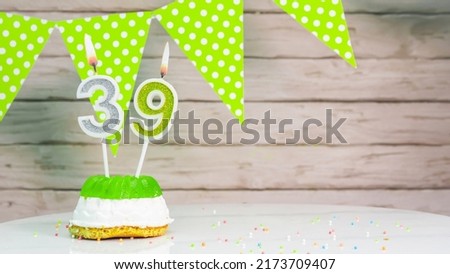 Beautiful festive background with the number 39 with a cake and lit candles, space saving for any holiday. Garland with birthday decorations for a postcard.Decorations are multi-colored festive