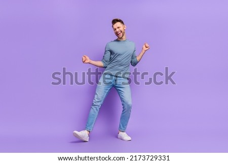 Photo of adorable lucky guy wear grey shirt having fun dancing rising fists isolated violet color background