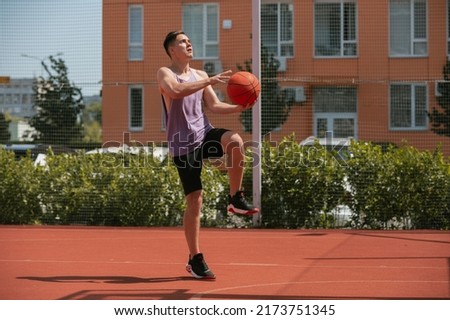 young guy plays basketball on the basketball court. throws the ball into the ring. doing sports. healthy body and healthy lifestyle