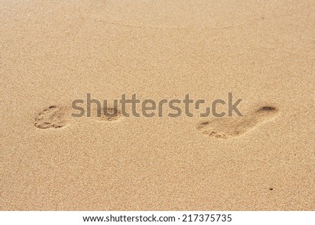 Footsteps on the yellow sand of the beach
