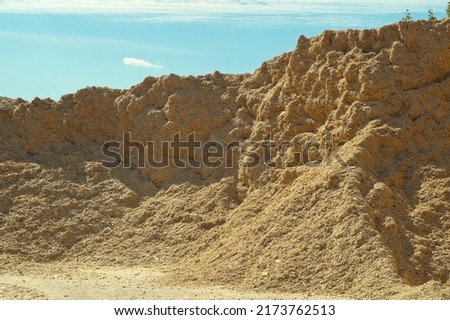 a product of wood processing, in the photo mountains of wood chips and sawdust against a blue sky.