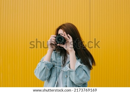 portrait of a young woman holding a camera and taking a photo
