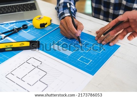 Architects or engineering work with blueprints and discuss projects together at the meeting in the office, and structural analysis of project types.