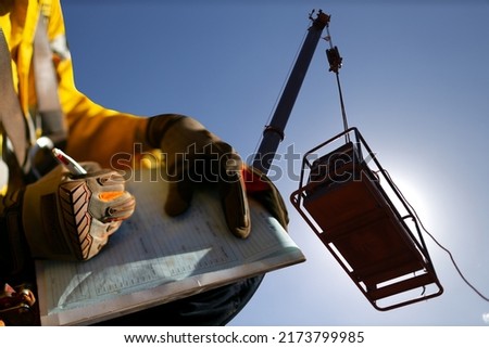 Construction miner supervisor wearing  safety glove signing working at height working permit on open field job site prior to starting high risk crane lifting at construction mine site Australia Royalty-Free Stock Photo #2173799985