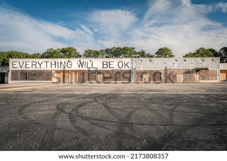 "Everything Will Be OK" reads the sign on the boarded-up storefront overlooking an empty lot. 