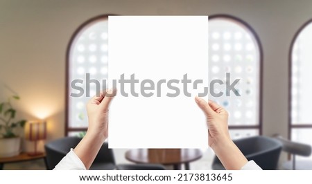 Hands holding white empty paper at restaurant background.