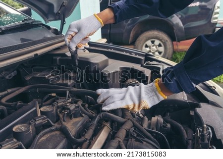 Car Mechanic man hand checking dipstick engine oil car mechanical on site service. Close up hand man check engine oil level Locate dipstick, wipe clean, check dipstick level before fill up engine oil Royalty-Free Stock Photo #2173815083