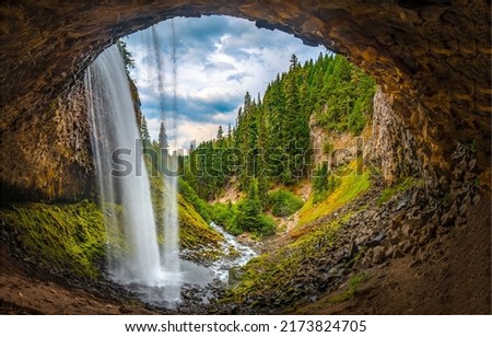 Waterfall over a cave in the forest. Waterfall river at cave