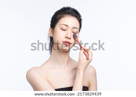 Asian girl doing makeup on white background
