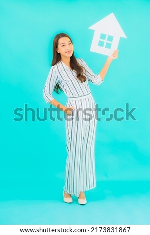 Portrait beautiful young asian woman show home or house sign on blue background
