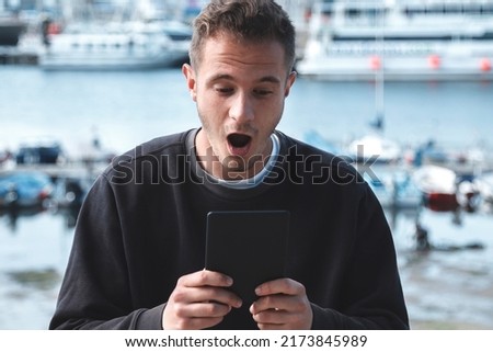 worried young tourist man looking at digital tablet with sea background