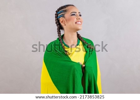 Brazilian fan holding Brazil flag on gray background. Young smiling brazilian woman smiling at camera with brazil flag Royalty-Free Stock Photo #2173853825