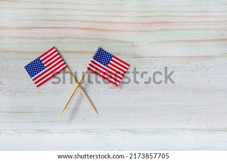 Closeup studio top view shot of four small miniature paper pride American USA United States of America country national toothpick stick flags placed on old vintage wooden background with copy space.