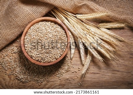 Bowl of rye grains and ears on wooden table, top view Royalty-Free Stock Photo #2173861161