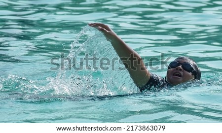 Motion photo of a child swimming in the pool using freestyle stroke. SSTKsports
