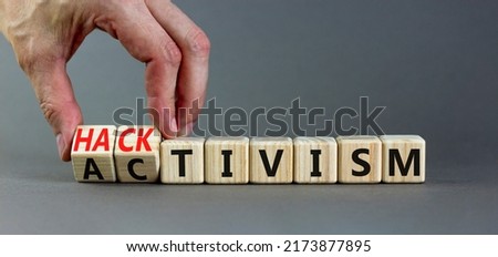Businessman turns wooden cubes and changes the word Activism to Hacktivism. Beautiful grey table grey background, copy space. 