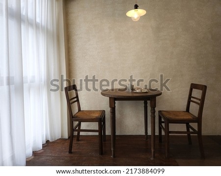 Vintage interior design of loft simple style of dining room. Plate of foods on a wooden round tables, with wooden chairs, wooden floor, a retro grunge mock-up wall, white curtain and a hanging lamp.