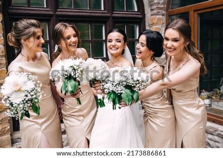 Group portrait of the bride and bridesmaids. A bride in a wedding dress and bridesmaids in golden dresses hold stylish bouquets of flowers on their wedding day. Royalty-Free Stock Photo #2173886861