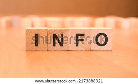 four wooden blocks with the letters Info - on the bright surface of a blue table. the inscription on the cubes is reflected from the surface