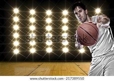 Basketball player on a  white uniform, in front of lights.