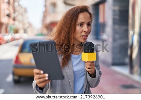 Young woman reporter working using microphone and touchpad at street Royalty-Free Stock Photo #2173926901